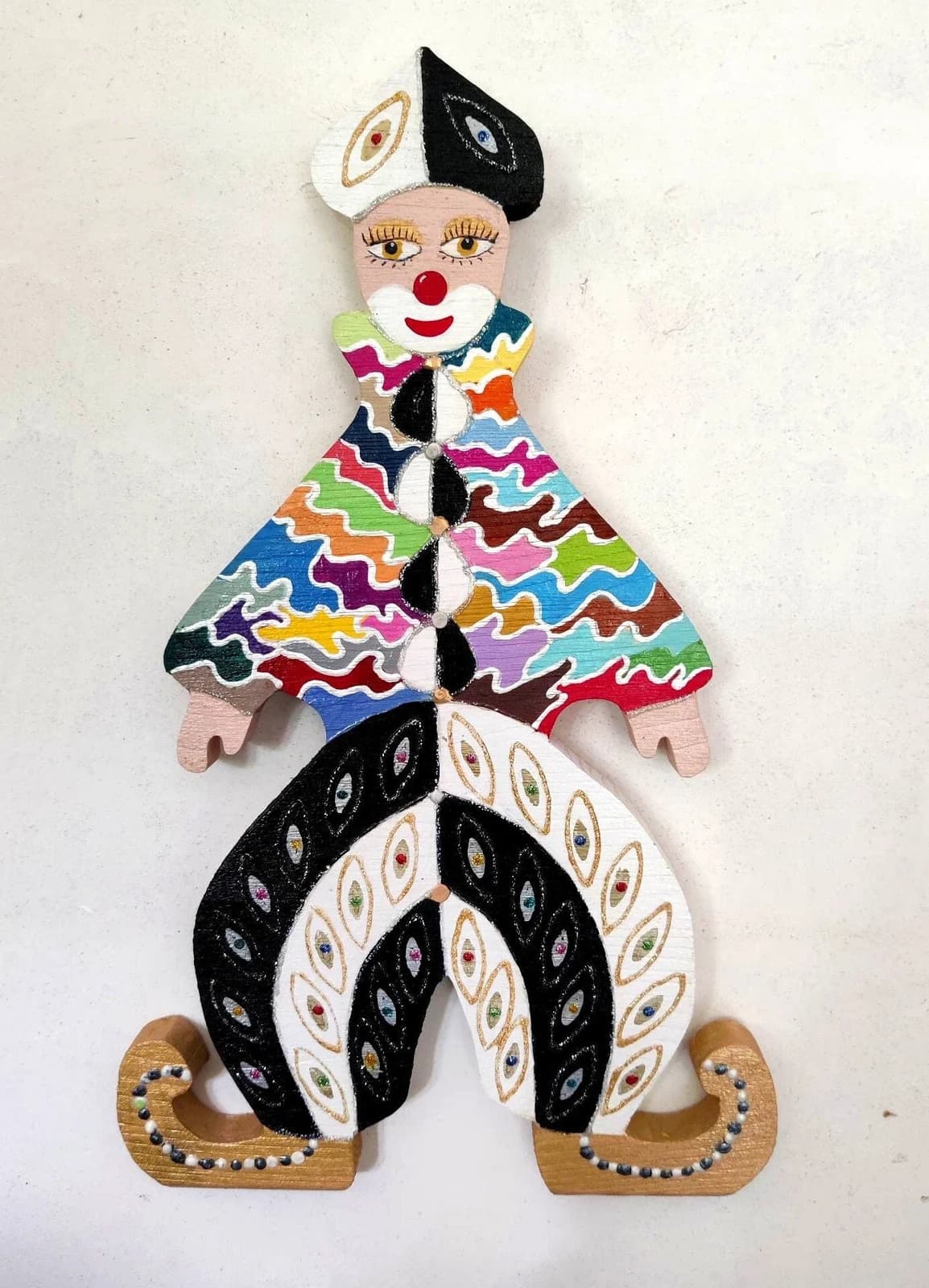 Clown mural en bois découpé peint à la main, veste multicolore et pantalon bouffant noir et blanc.