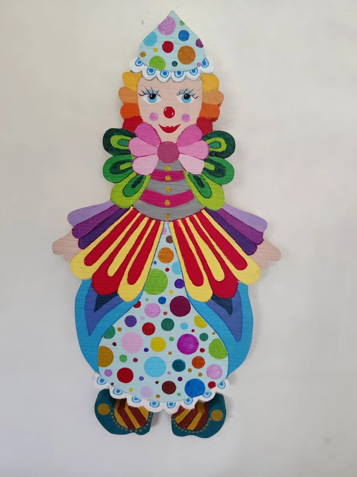 Clown mural en bois peint à la main avec robe à pois multicolores, chapeau pointu et grand col papillon.
