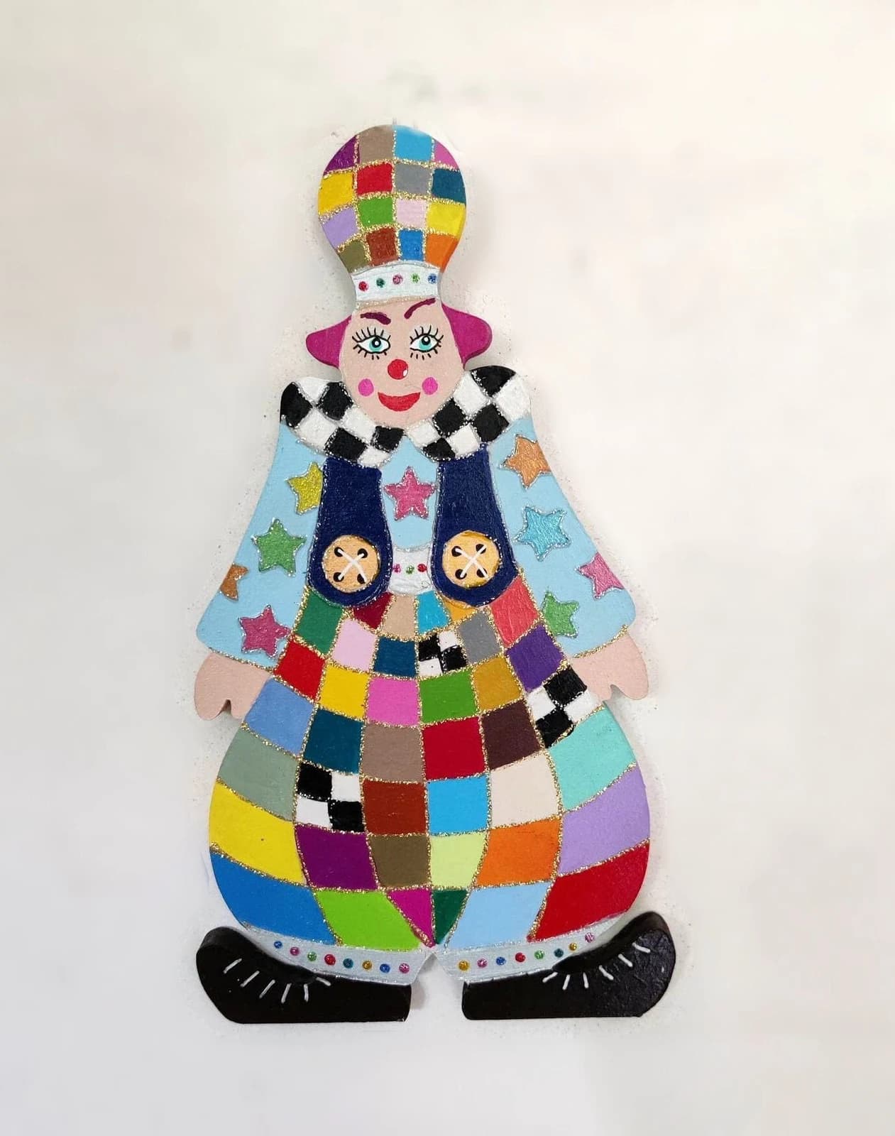 Clown mural en bois peint de motifs multicolores façon arlequin avec chapeau en forme d'ampoule et étoiles