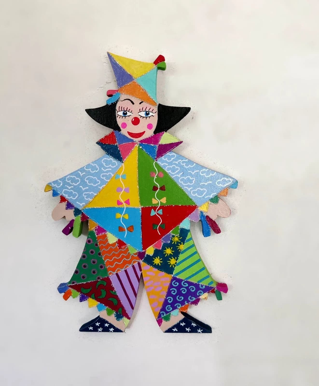 Figurine murale de clown Tako en bois peint aux motifs multicolores variés et chapeau pointu.