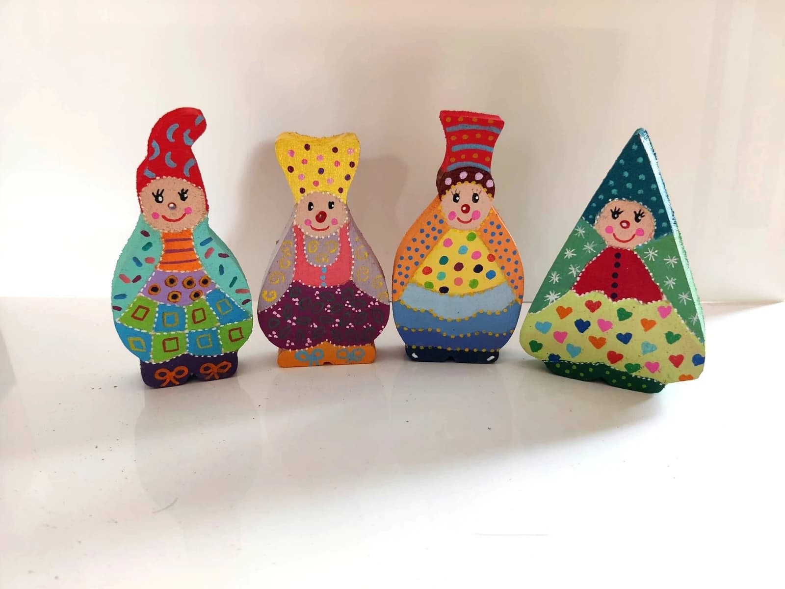 Quatre figurines lutins Farfs en bois peintes de motifs colorés et chapeaux variés