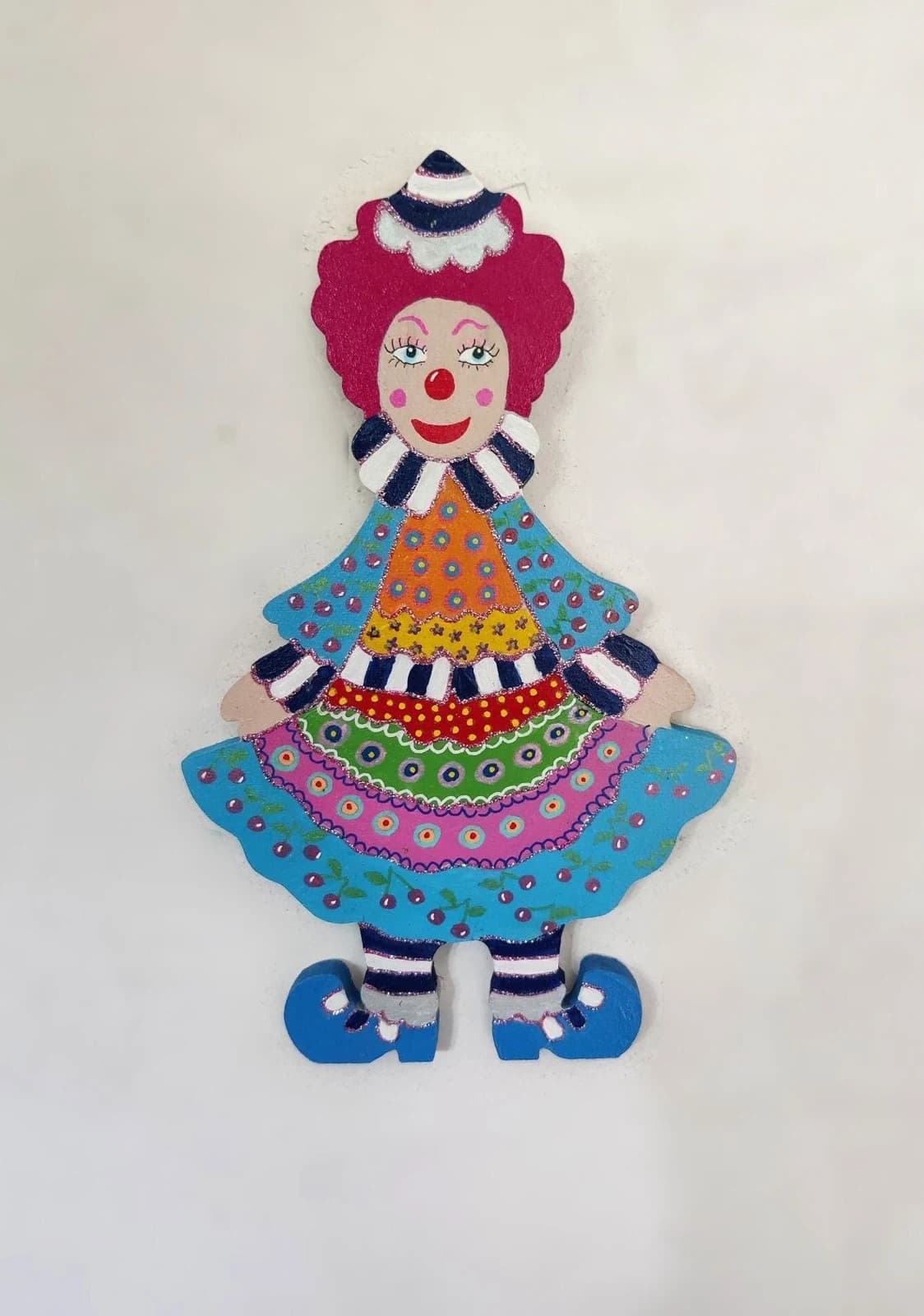 Figurine murale de clown en bois peint, robe bleue à cerises colorée et cheveux rouges.