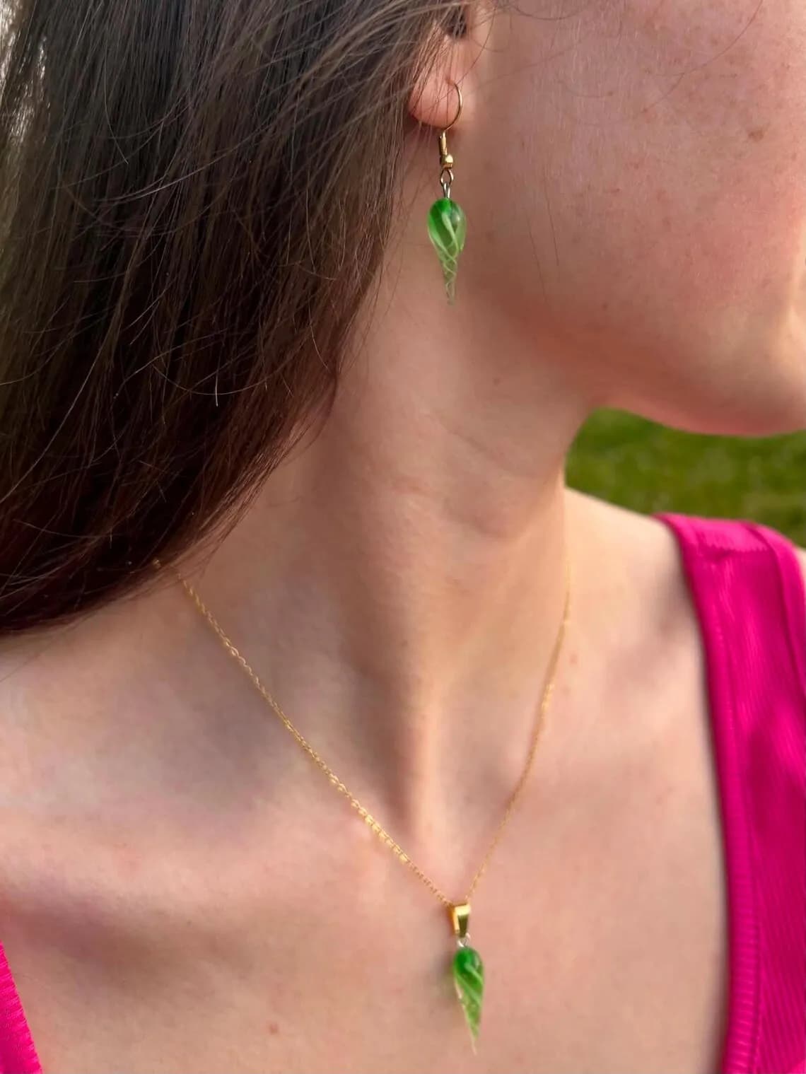 Boucle d'oreille pendante verte torsadée portée avec un collier assorti