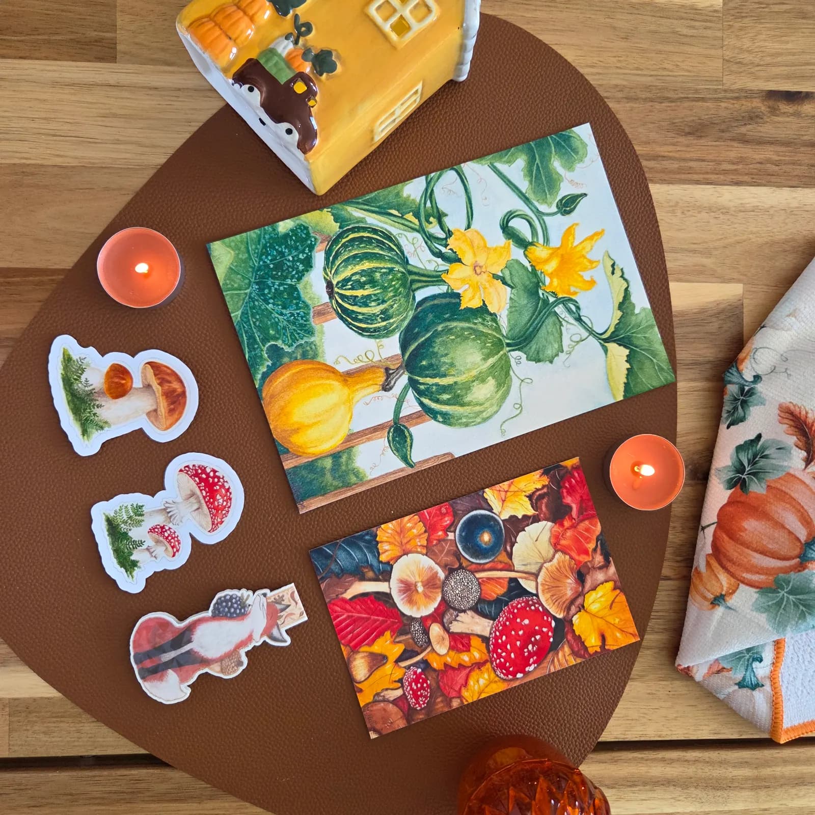 Papeterie d'automne avec deux tirages illustrés, stickers champignons et marque-page renard entourés de bougies.