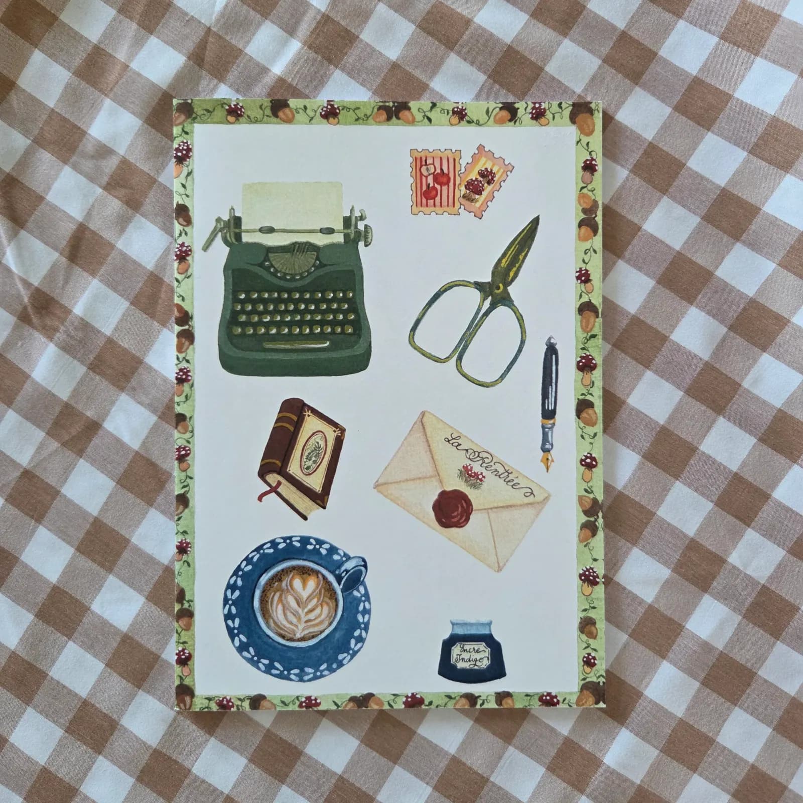 Couverture du carnet illustré d'une machine à écrire, tasse de café, lettre et frise de glands et champignons.