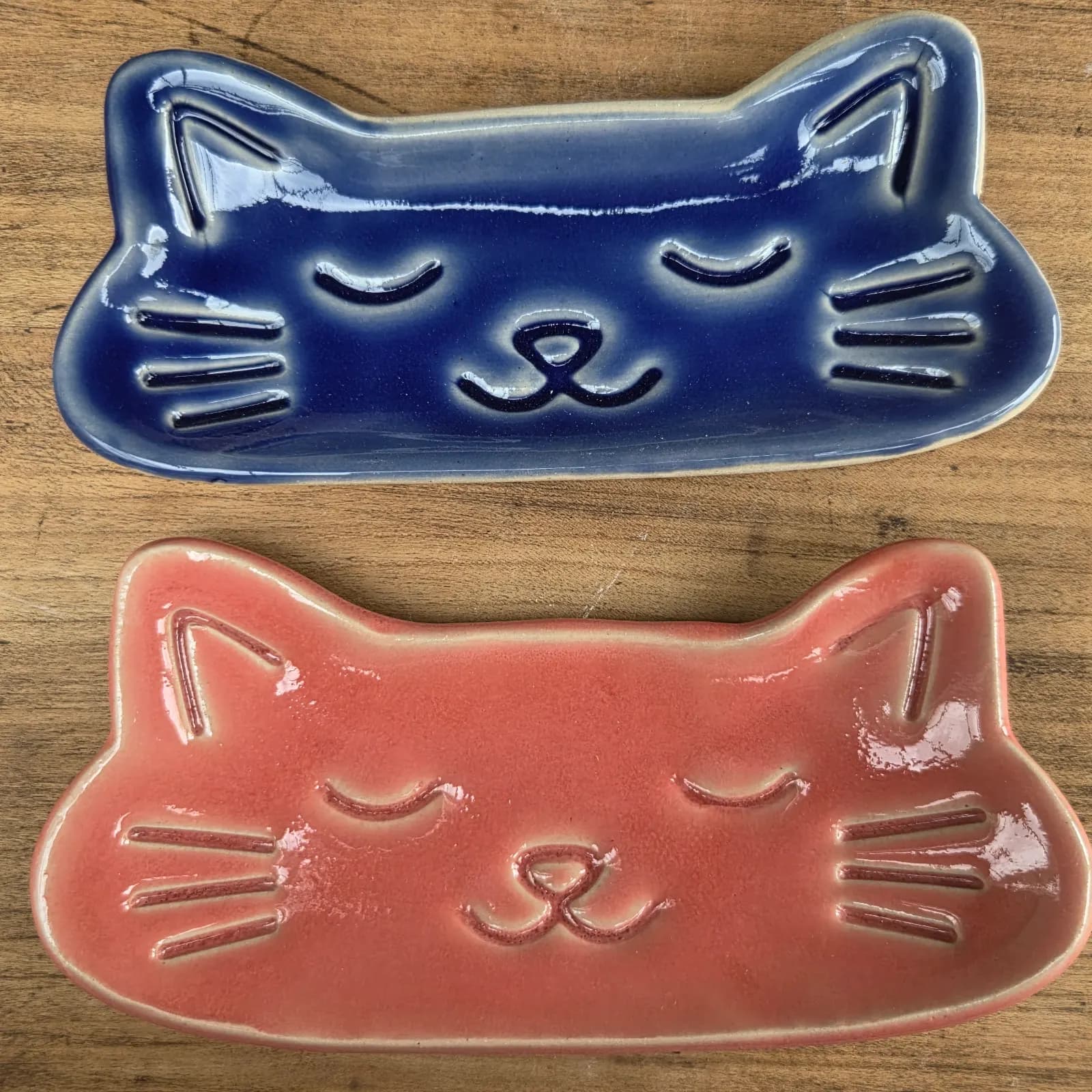 Gros plan sur l'émail bleu brillant et les motifs en relief du visage de chat sur le plateau en céramique.