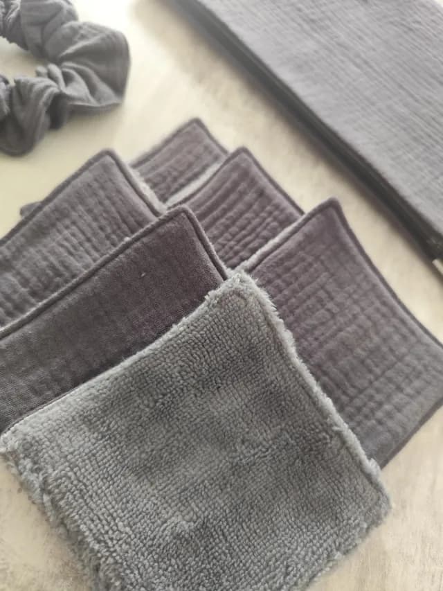Détail des lingettes lavables grises texturées présentées avec le chouchou et la pochette