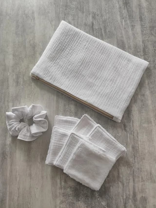 Pochette zippée blanche, lingettes réutilisables carrées et chouchou blanc posés à plat