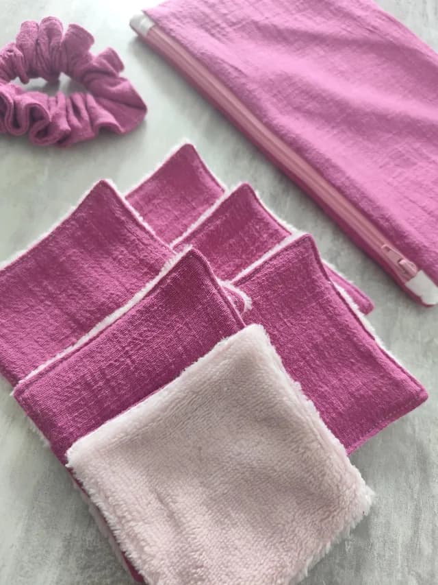 Gros plan sur les lingettes lavables roses et douces, avec la pochette zippée et le chouchou assortis.