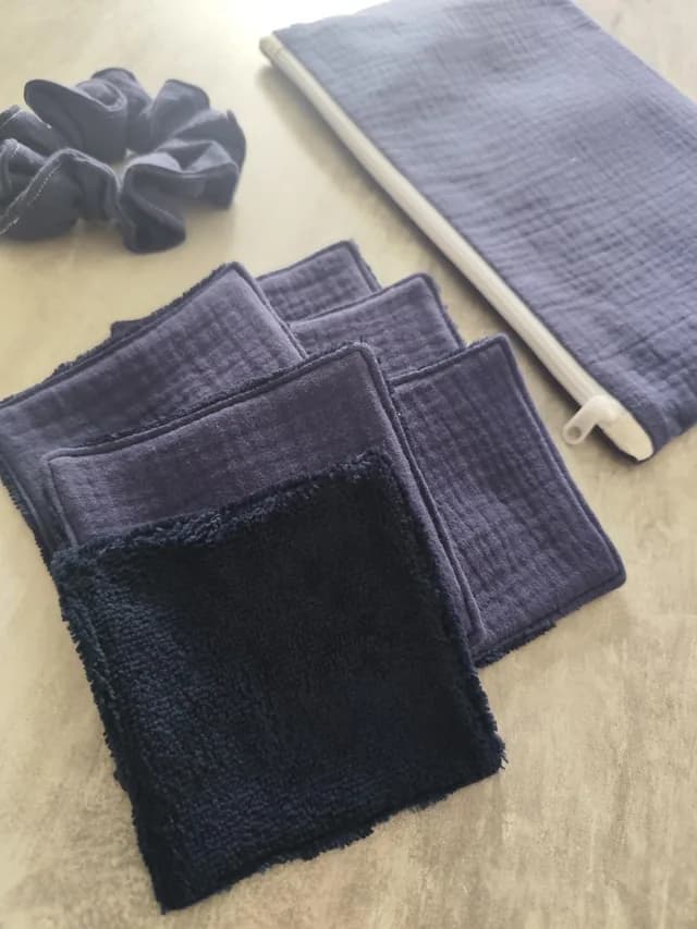 Gros plan sur les lingettes lavables en tissu bleu et éponge douce, avec pochette et chouchou en fond.