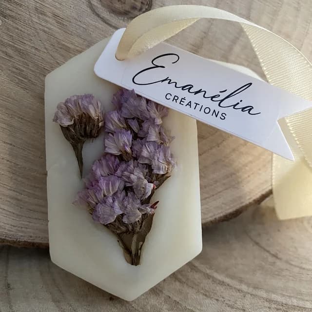 Suspension hexagonale blanche ornée de fleurs séchées violettes avec ruban et étiquette sur fond en bois.