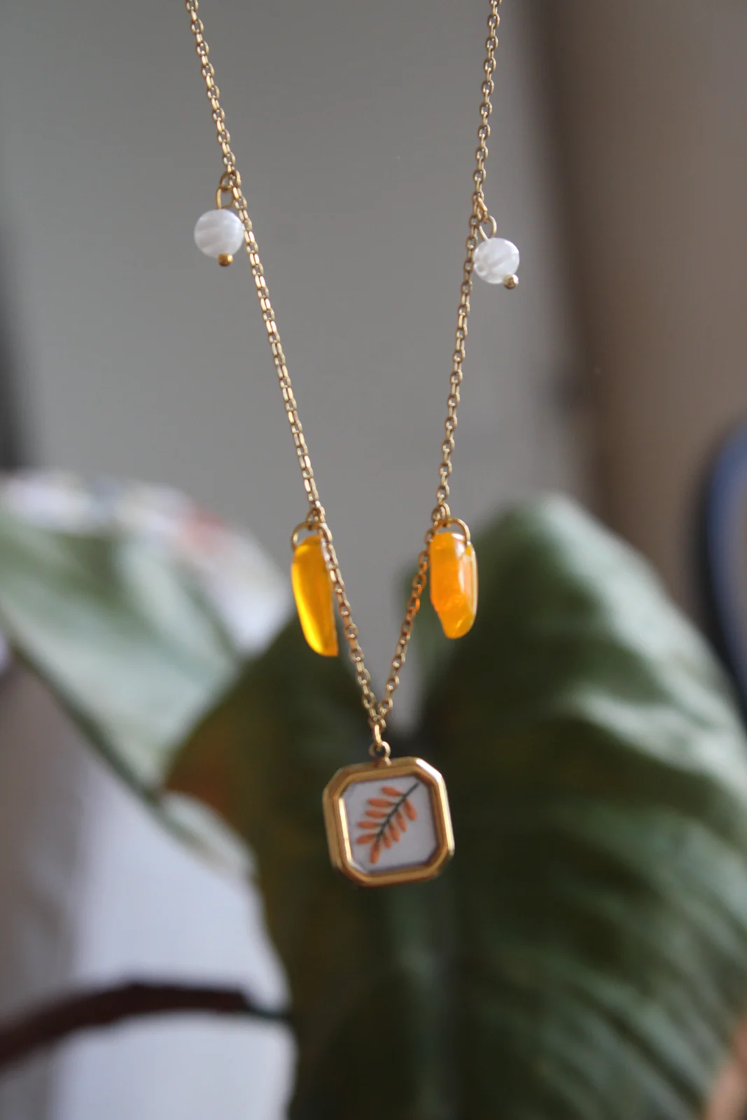 Collier doré suspendu avec pampilles orange, perles blanches et pendentif motif branche orange