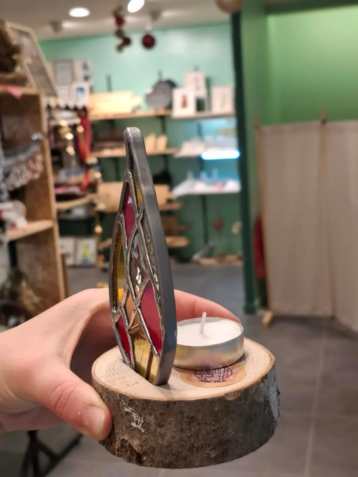 Vue de profil du photophore avec bougie chauffe-plat posée sur le socle en bois derrière le vitrail