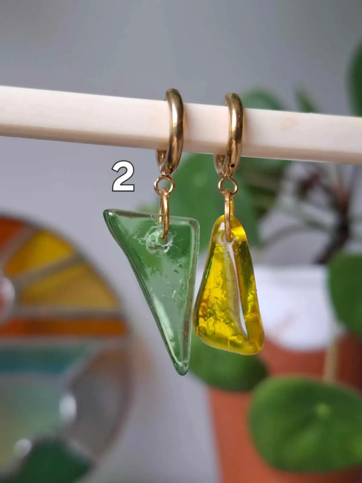 Boucles d'oreilles asymétriques suspendues avec un pendant en verre vert et un autre en verre jaune.
