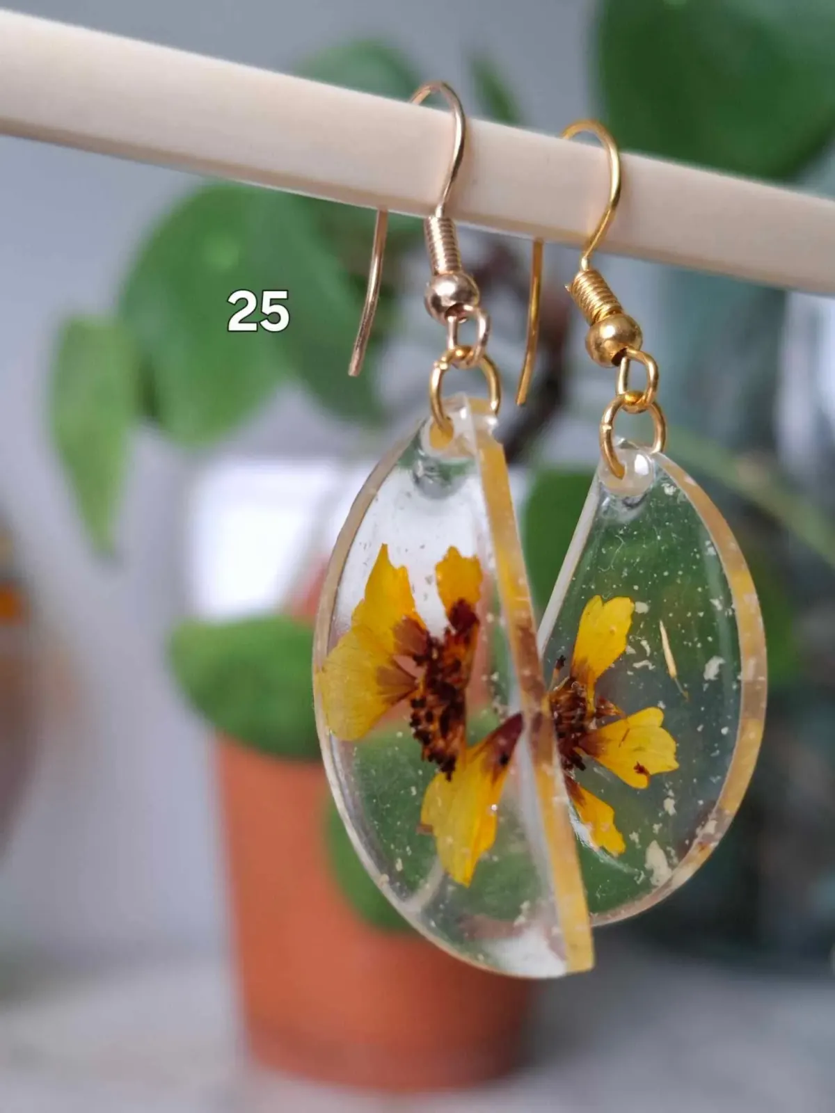 Boucles d'oreilles demi-lune transparentes en résine avec de petites fleurs séchées jaunes.