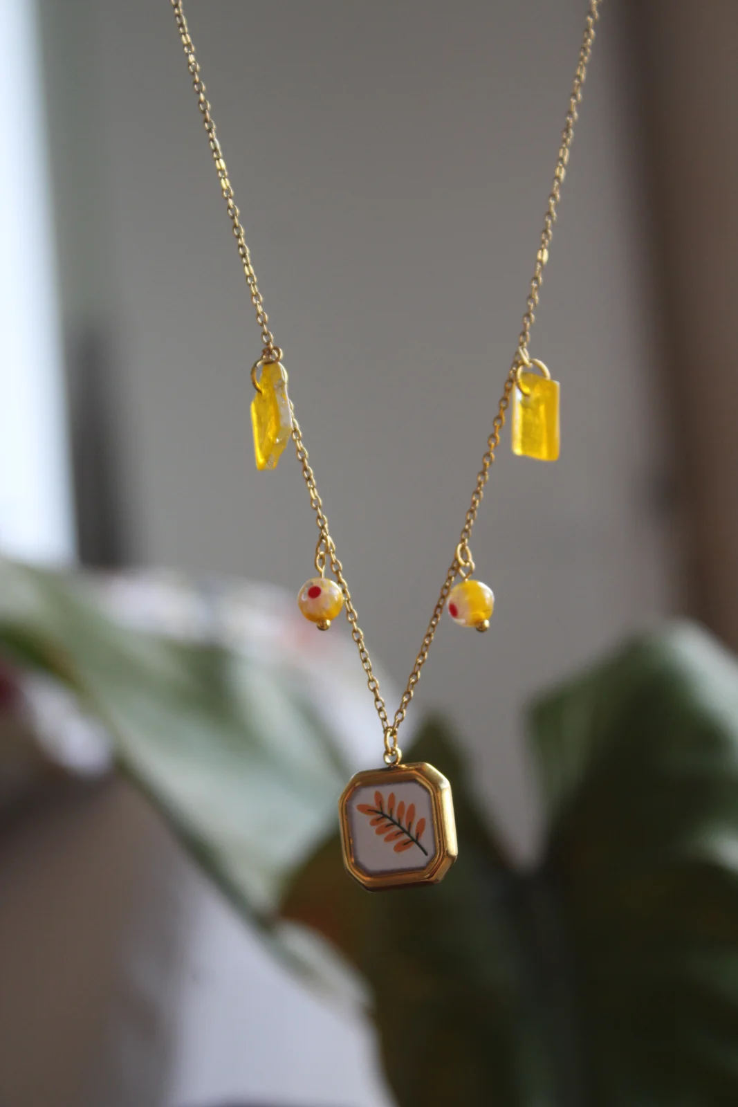 Collier à pampilles jaune et pendentif motif végétal