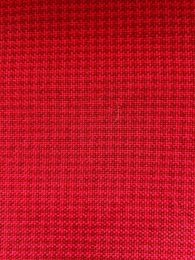 Gros plan sur le tissage artisanal régulier du textile rouge