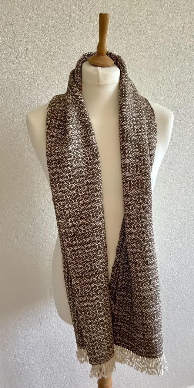 Écharpe marron et blanche à franges drapée sur un mannequin de couture blanc