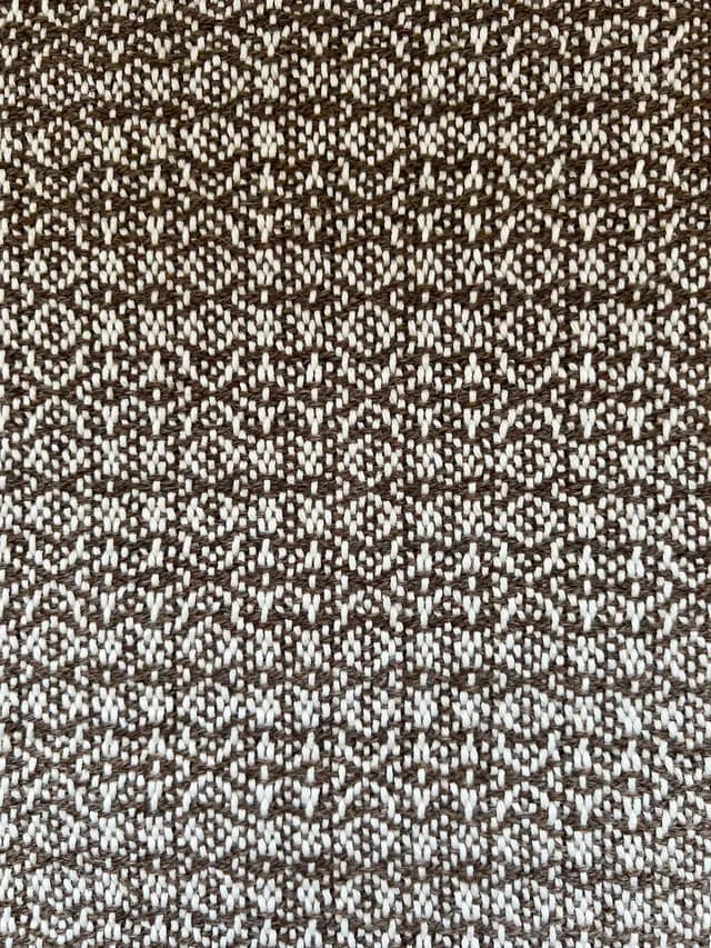 Gros plan sur les motifs géométriques d'un tissage artisanal marron et blanc