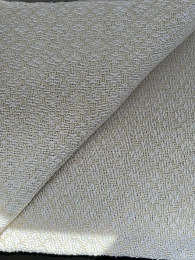 Plaid tissé artisanal aux teintes écru et blanc avec pan replié montrant le motif losange