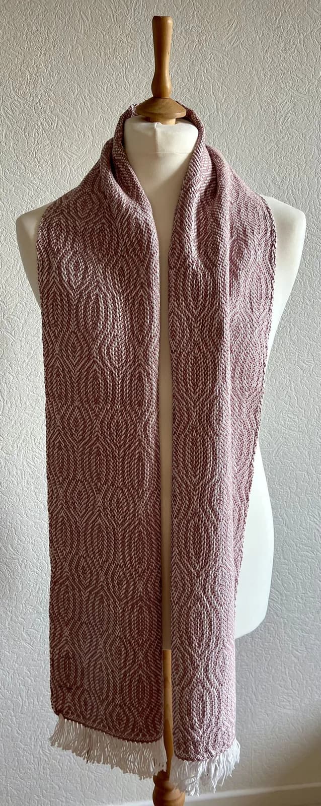 Écharpe tissée rose poudré et blanche à motifs géométriques présentée sur un mannequin de couture.
