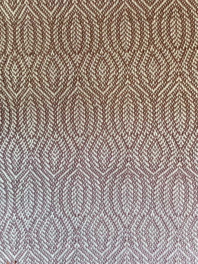 Gros plan sur le tissage artisanal aux motifs de losanges texturés roses et blancs.
