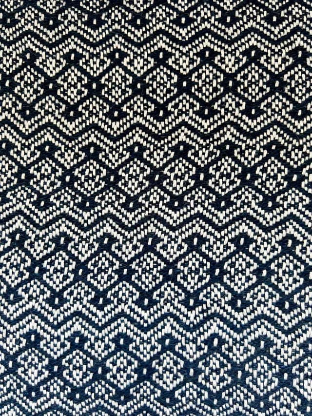 Détail rapproché du tissage bleu et blanc aux motifs géométriques de losanges et chevrons.