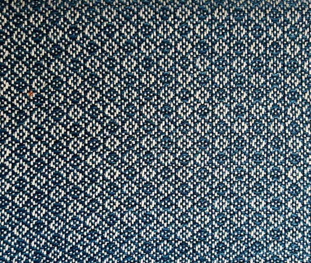 Gros plan sur le motif géométrique tissé en fils bleus et gris.