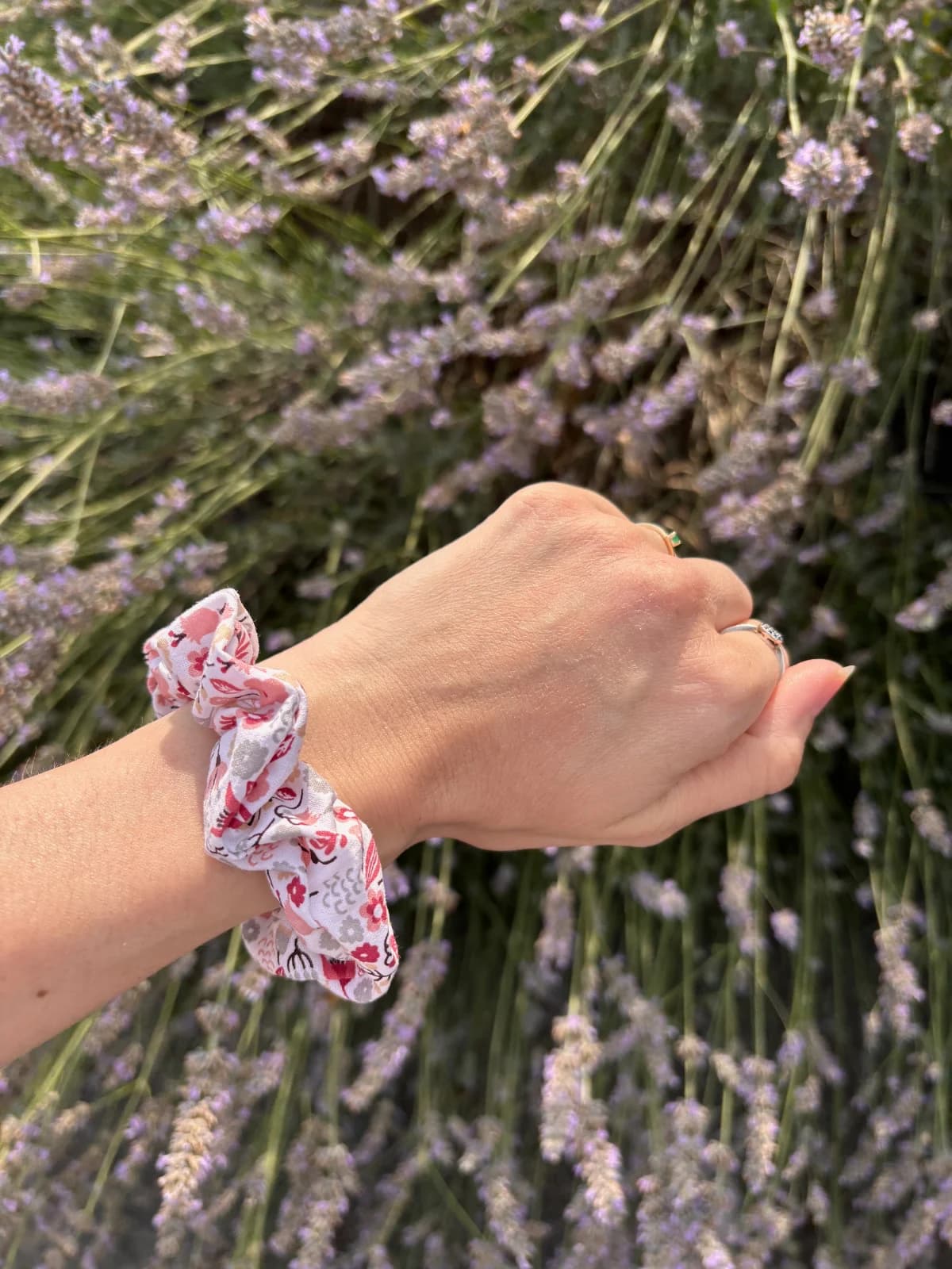 Chouchou élastique à fleurs roses porté au poignet devant des lavandes fleuries