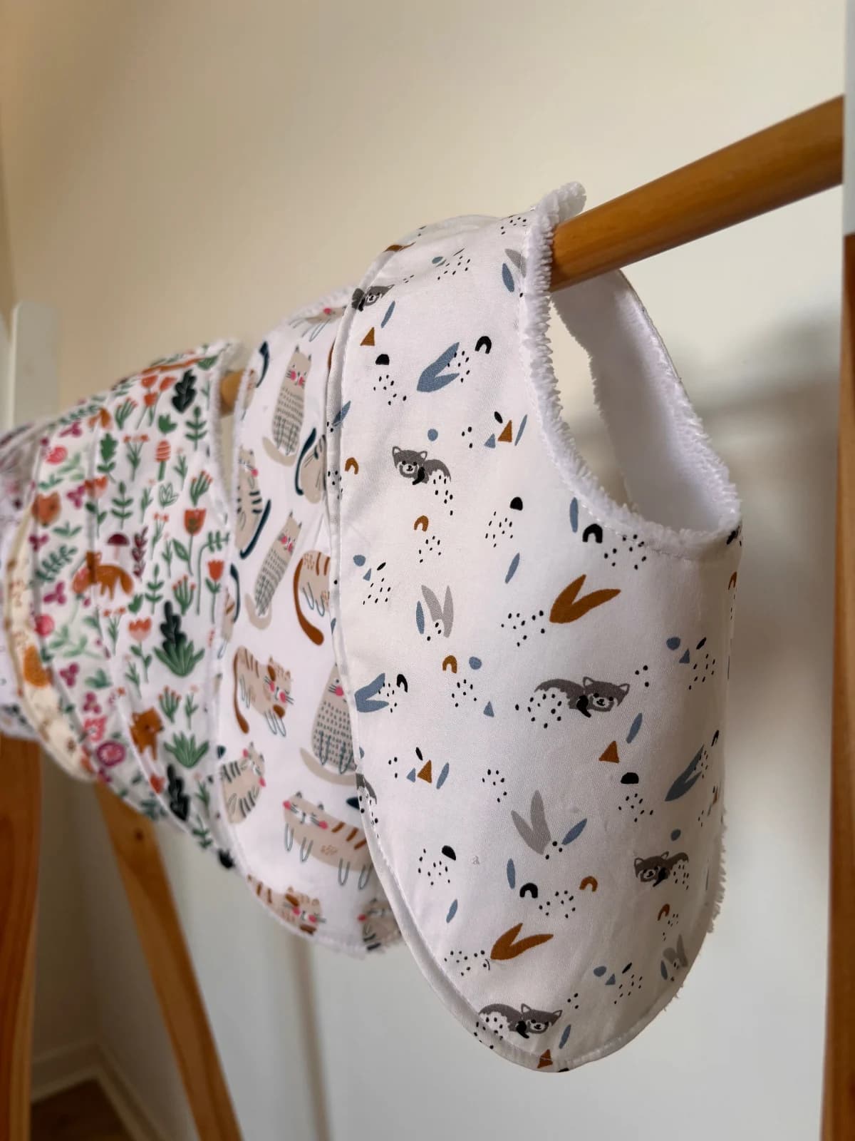 Bavoirs bandana bébé à motifs suspendus sur un support en bois avec doublure éponge blanche visible