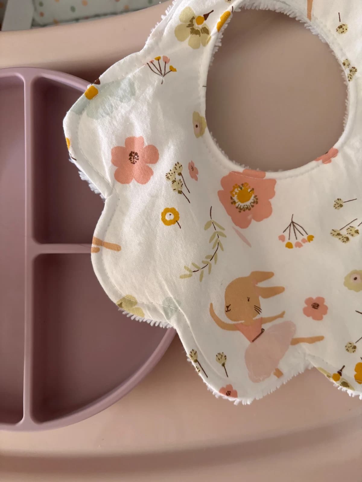 Gros plan sur les pétales du bavoir fleuri avec un motif de petit lapin ballerine et des fleurs roses.