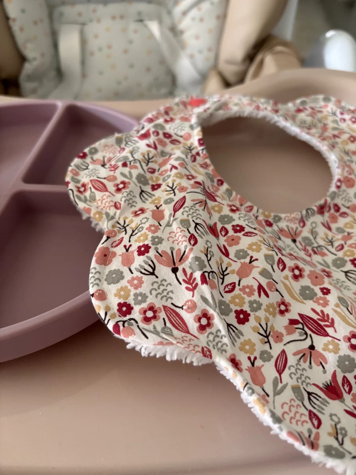 Bavoir bébé à découpe fleur en tissu imprimé floral bordé d'éponge blanche.