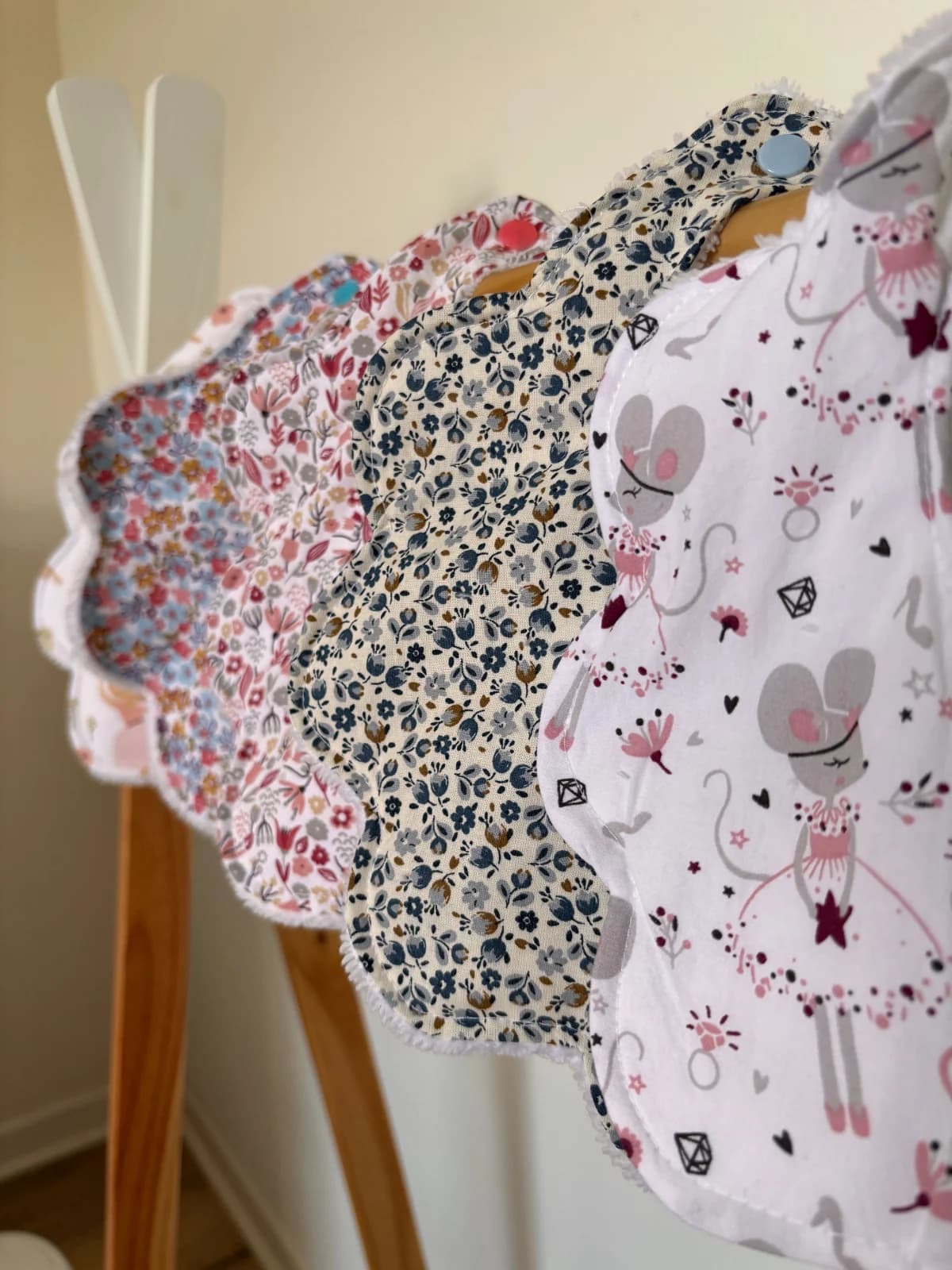 Rangée de bavoirs en forme de fleur aux motifs variés suspendus sur un portant