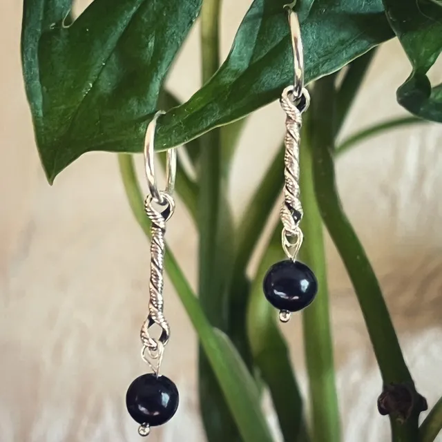 Gros plan sur les boucles d'oreilles créoles torsadées en argent et perles d'eau douce