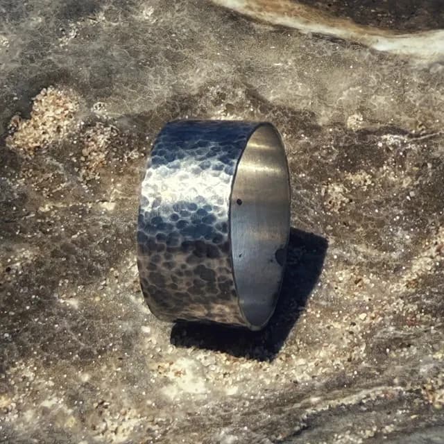 Anneau large en argent 925 martelé et patiné posé sur une roche