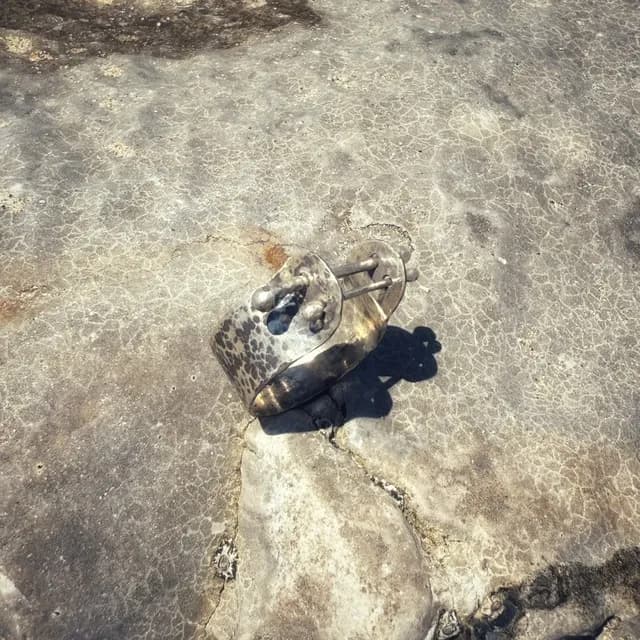 Vue du dessus de la bague argentée texturée avec système de tiges traversantes sur fond minéral.