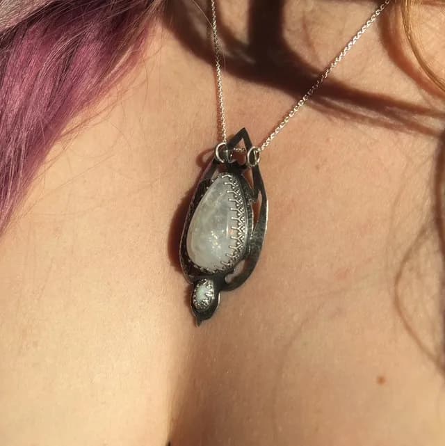Vue de profil du pendentif en argent texturé et pierre irisée porté sur chaîne fine