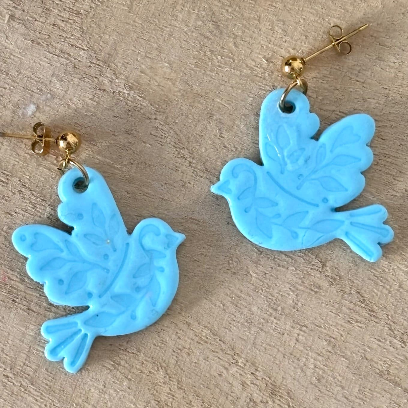 Gros plan sur les deux oiseaux bleus en pâte polymère aux motifs végétaux en relief