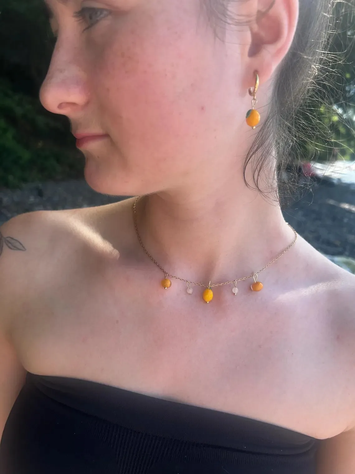 Paire de boucles d'oreilles citron jaune et feuille verte suspendues sur un présentoir