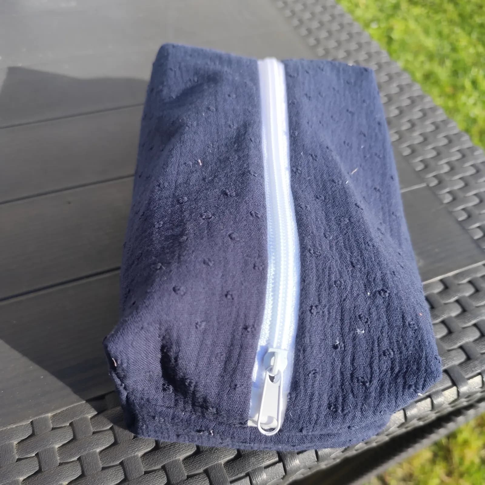 Trousse rectangulaire bleu marine en tissu texturé avec fermeture zippée blanche sur le dessus