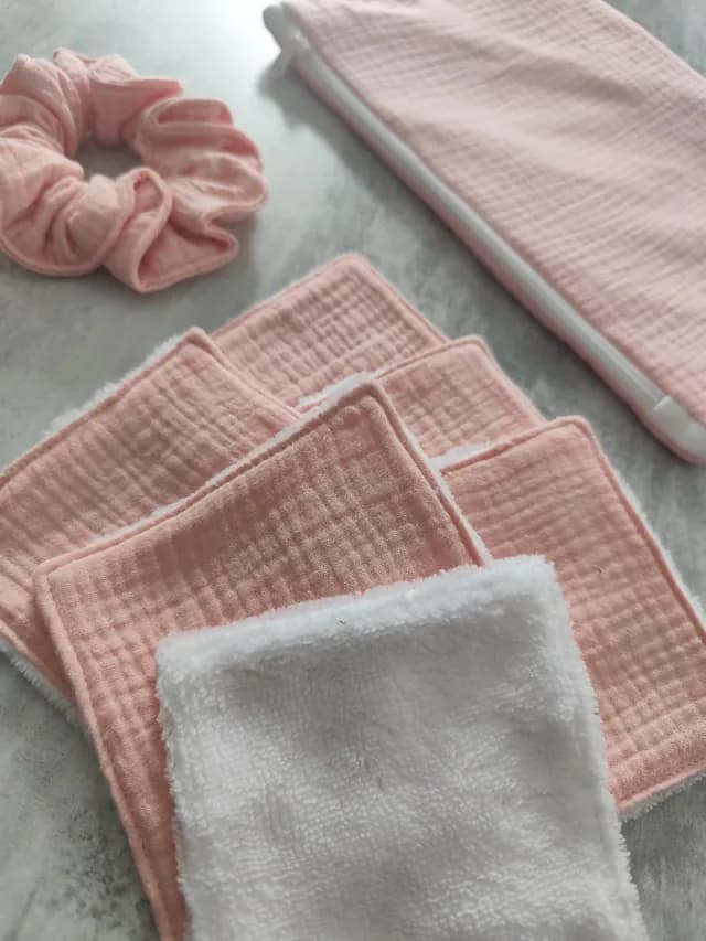 Détail des lingettes réutilisables roses et blanches, avec chouchou et trousse coordonnée.