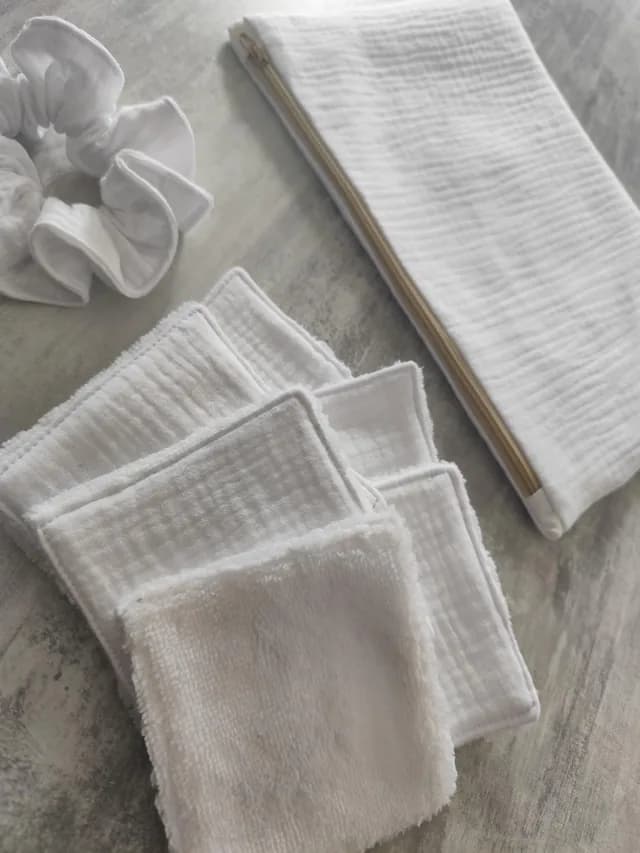 Vue rapprochée des lingettes lavables blanches avec le chouchou et la pochette assortie