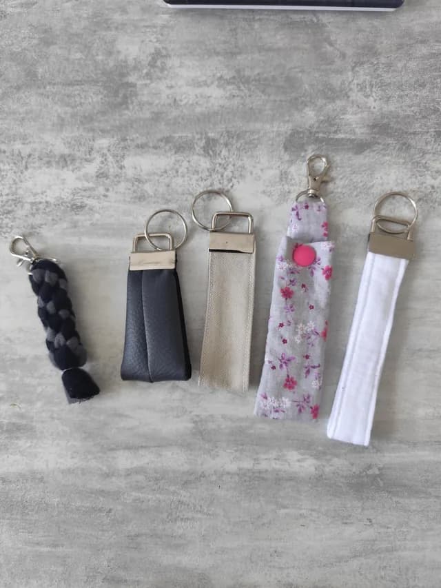Ensemble de cinq porte-clés artisanaux variés présentés à plat sur une surface texturée grise